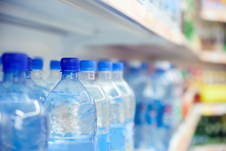 Close-up of blue-capped plastic water bottles on a store shelf.