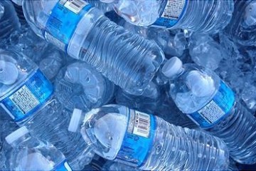 Plastic water bottles with blue labels lie in a pile of ice.
